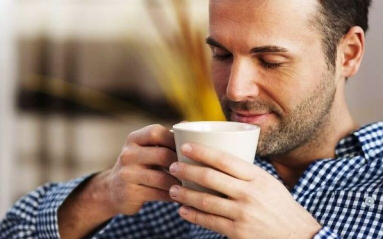 Un homme boit une gorgée de thé à l’épilobe pour augmenter sa puissance